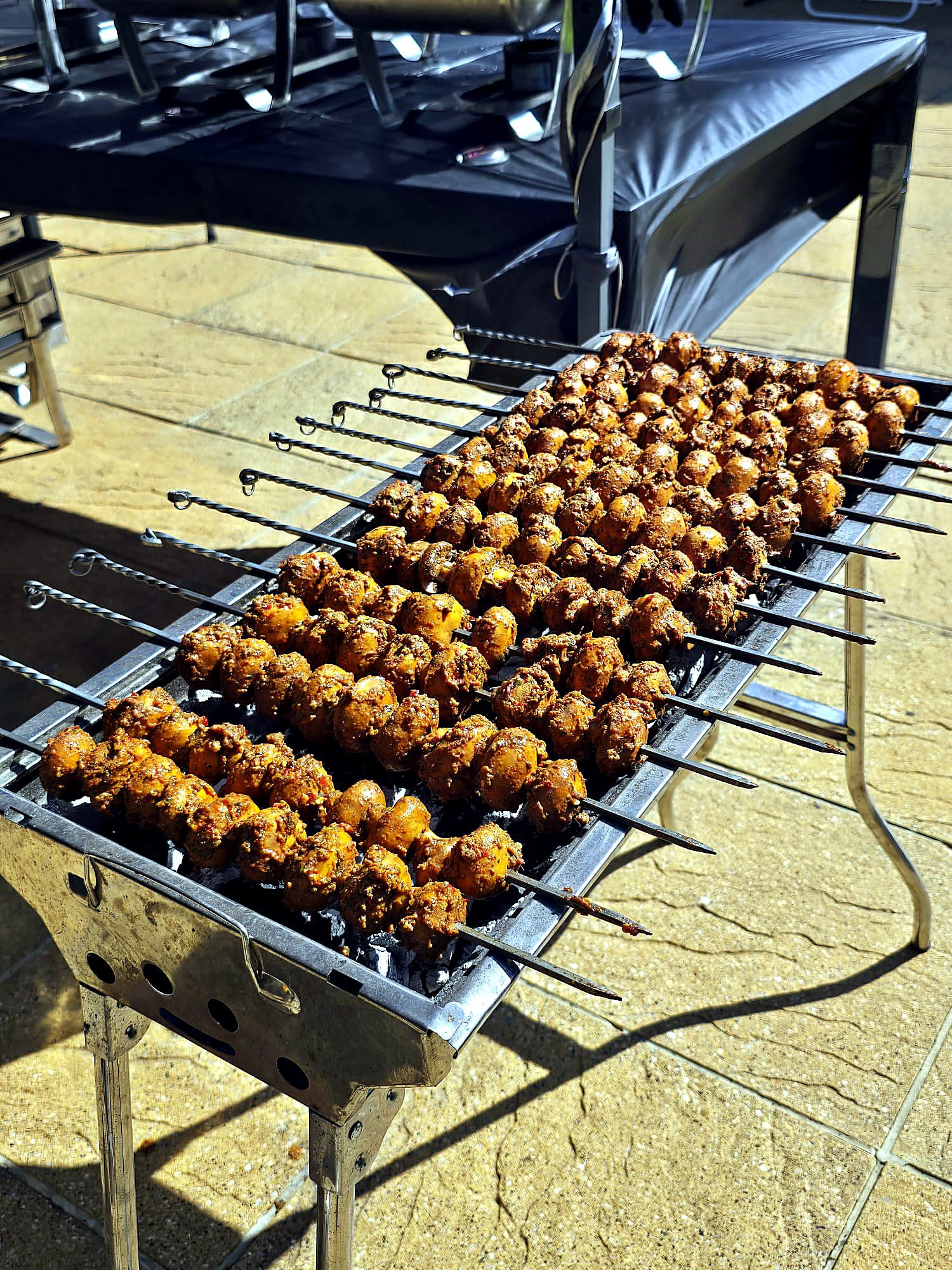 Rows of marinated chicken skewers grilling over hot charcoal